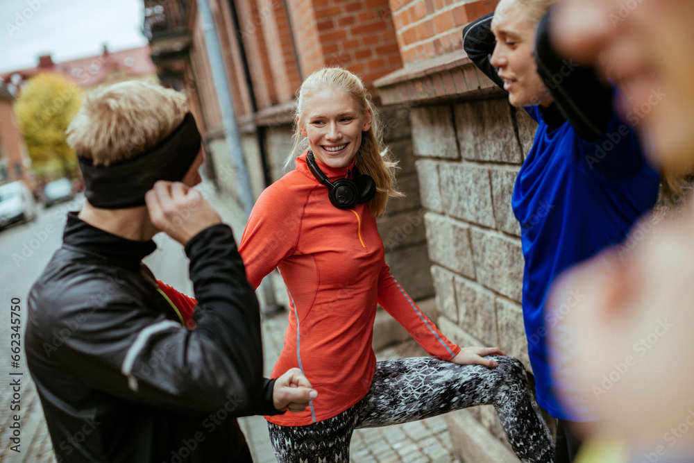 Fototapeta premium Young and diverse group of friends stretching and getting ready to exercise and jog in the city