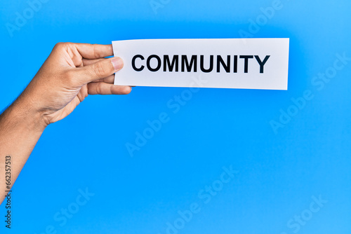 Hand of caucasian man holding paper with community word over isolated white background