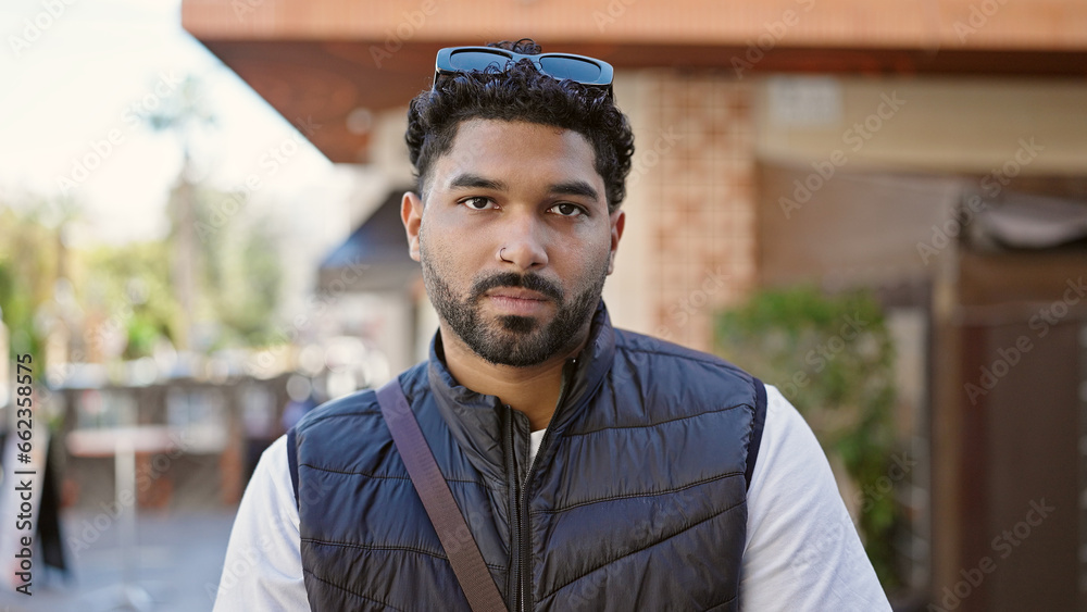 African american man standing with serious expression at coffee shop terrace African american man standing with serious expression at coffee shop terrace