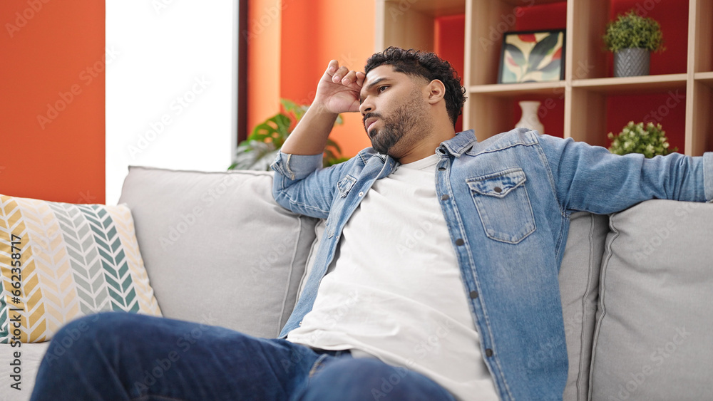 African american man sitting on sofa with serious expression at home