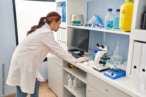 Young caucasian woman scientist using computer at laboratory