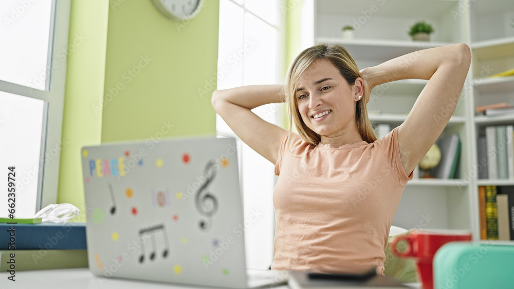 Young blonde woman student using computer relaxing with hands on head at library university Young blonde woman student using computer relaxing with hands on head at library university