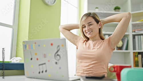 Young blonde woman student using computer relaxing with hands on head at library university