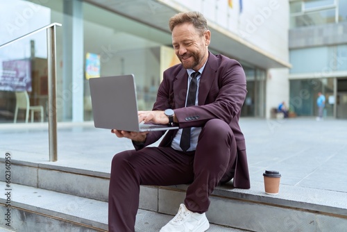 Middle age man business worker smiling confident using laptop at street