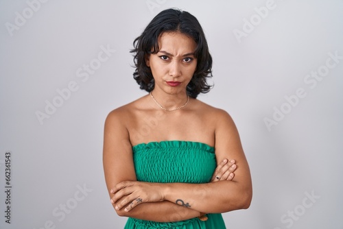 Young hispanic woman standing over isolated background skeptic and nervous, disapproving expression on face with crossed arms. negative person.
