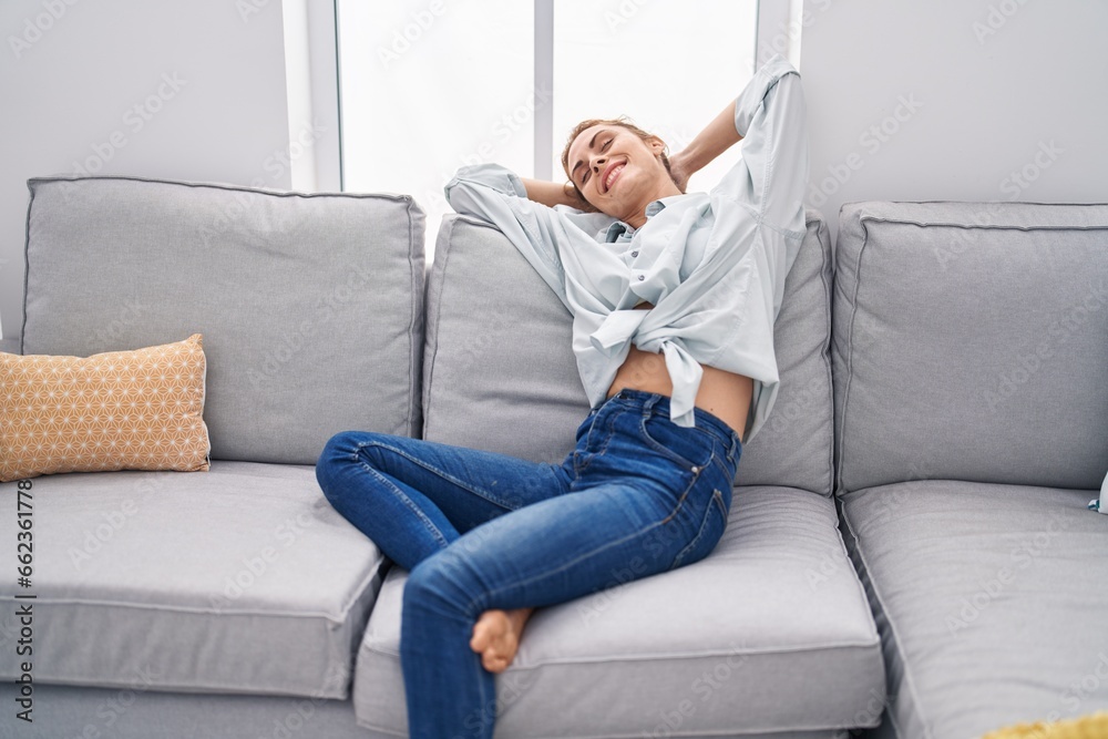 Young woman relaxed with hands on head sitting on sofa at home Young woman relaxed with hands on head sitting on sofa at home