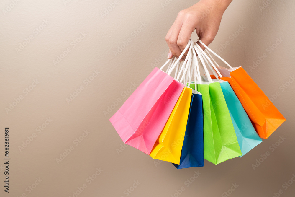 Hand holding multi colored gift or shopping bags isolated