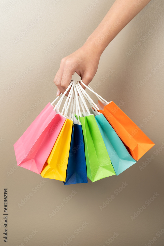 Hand holding multi colored gift or shopping bags isolated
