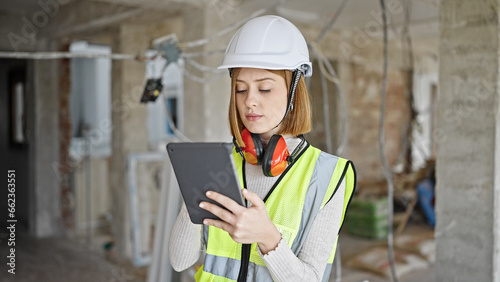 Young blonde woman architect using touchpad with serious expression at construction site