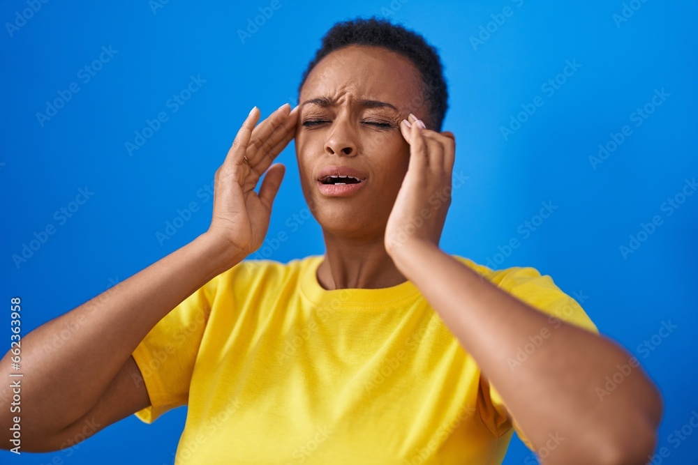 African american woman suffering for headache crying over isolated blue background African american woman suffering for headache crying over isolated blue background