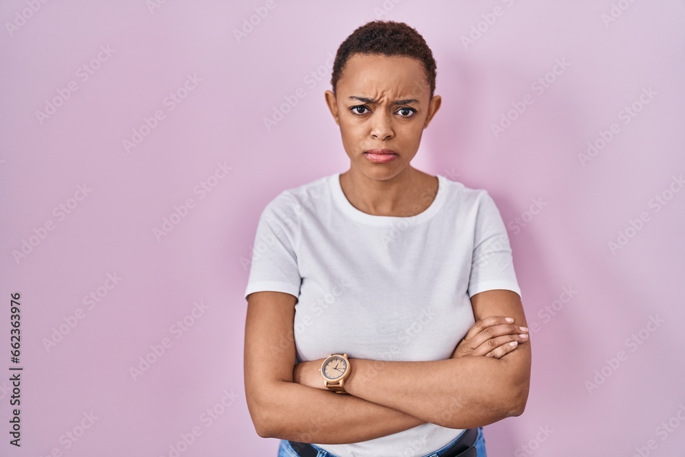 Obraz premium Beautiful african american woman standing over pink background skeptic and nervous, disapproving expression on face with crossed arms. negative person.
