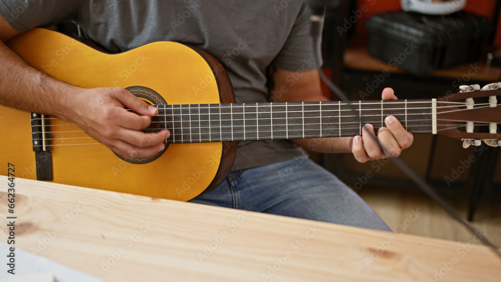 Obraz premium Young latin man musician playing classical guitar at music studio