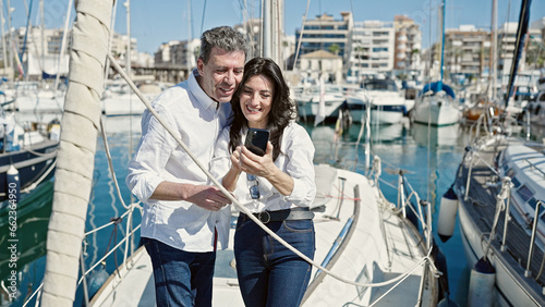 Senior man and woman couple smiling confident using smartphone at boat