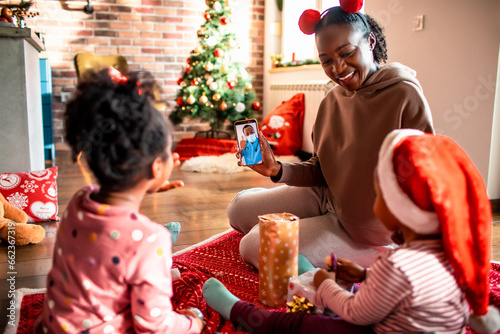 Young single mother talking to a pediatrician with his children on a video call at home photo