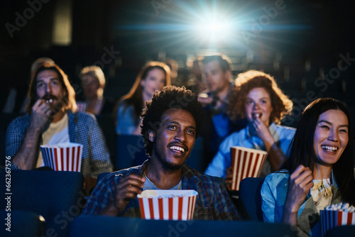 Young and diverse group of friends watching a movie in the movie theater photo