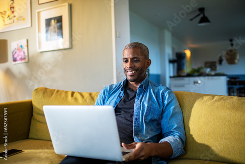 Middle aged man using the laptop on the couch at home photo