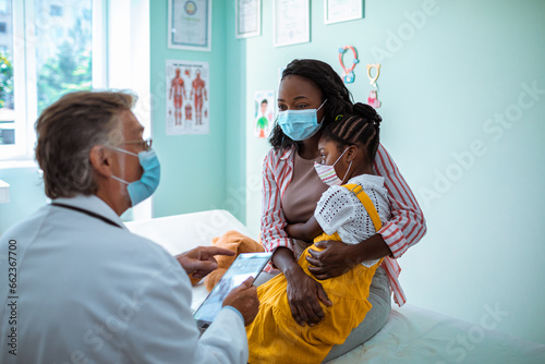 Young mother consulting a pediatrician about her daughter at the clinic photo
