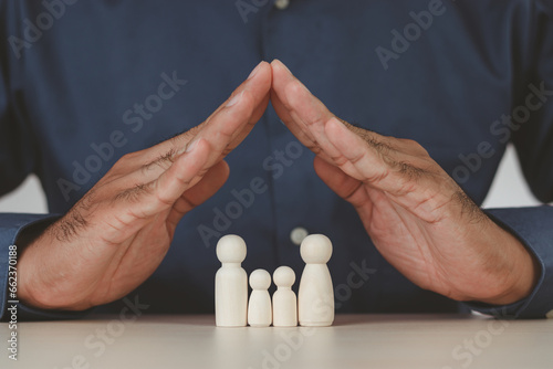 Man's hands protecting wooden figures of family members, Family relationship symbol, family home lockdown concept , Insurance and property investment, world mental health day. Wooden puppets.
