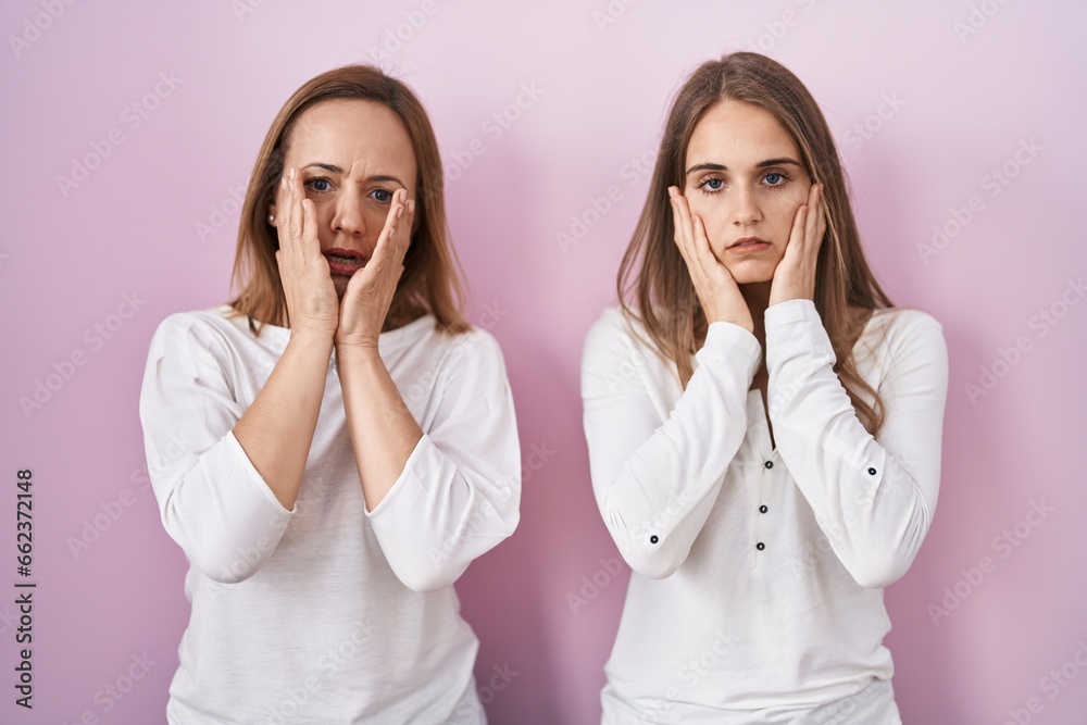 Middle age mother and young daughter standing over pink background tired hands covering face, depression and sadness, upset and irritated for problem Middle age mother and young daughter standing over pink background tired hands covering face, depression and sadness, upset and irritated for problem