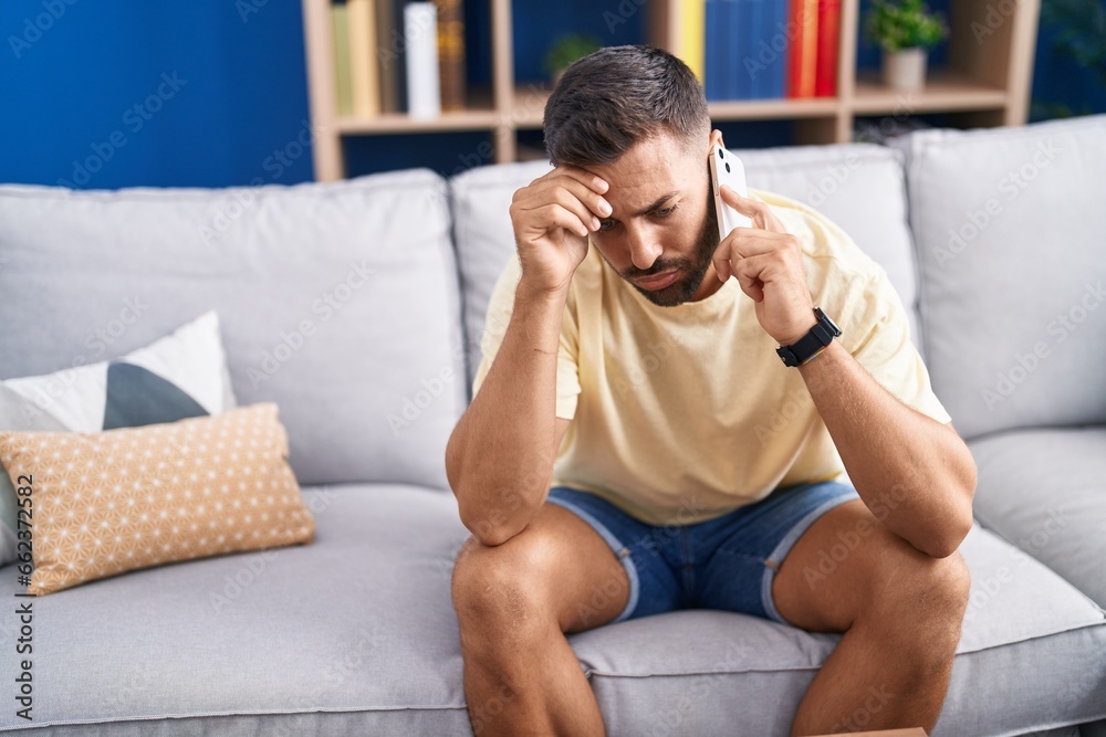 Young hispanic man talking on smartphone with worried expression at home Young hispanic man talking on smartphone with worried expression at home