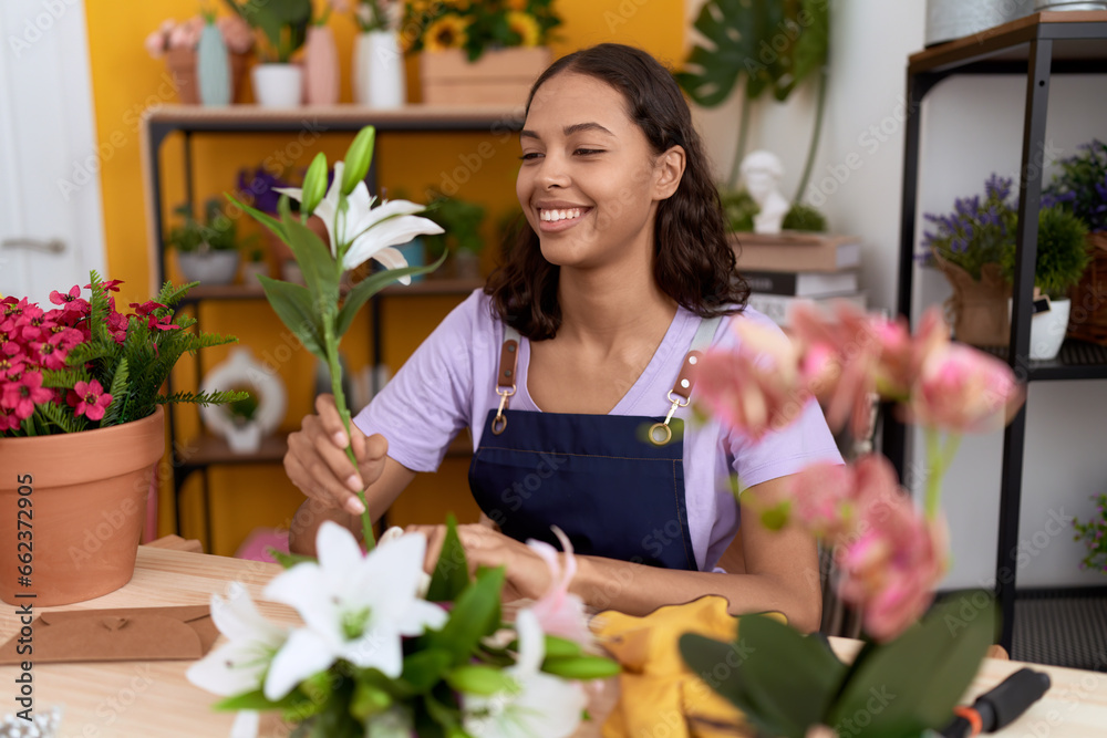 Young african american woman florist make bouquet of flowers at flower shop