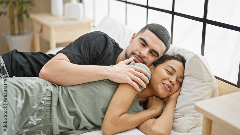 Beautiful couple in love hugging each other, lying comfortably on bed in cozy bedroom, relishing the relaxing morning sleep together Beautiful couple in love hugging each other, lying comfortably on bed in cozy bedroom, relishing the relaxing morning sleep together