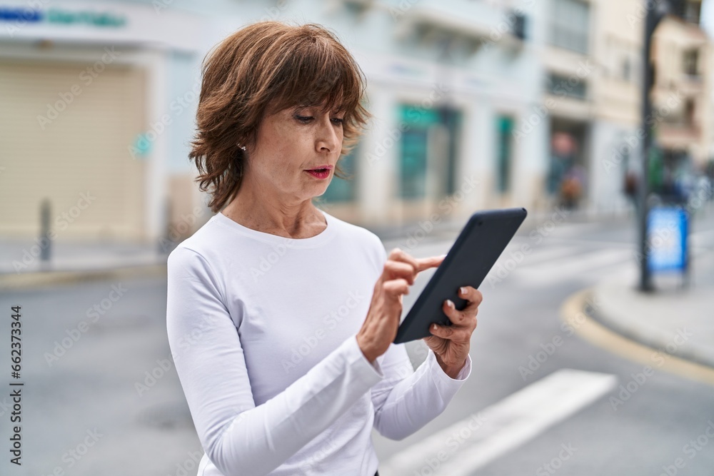 Middle age woman using touchpad with serious expression at street Middle age woman using touchpad with serious expression at street