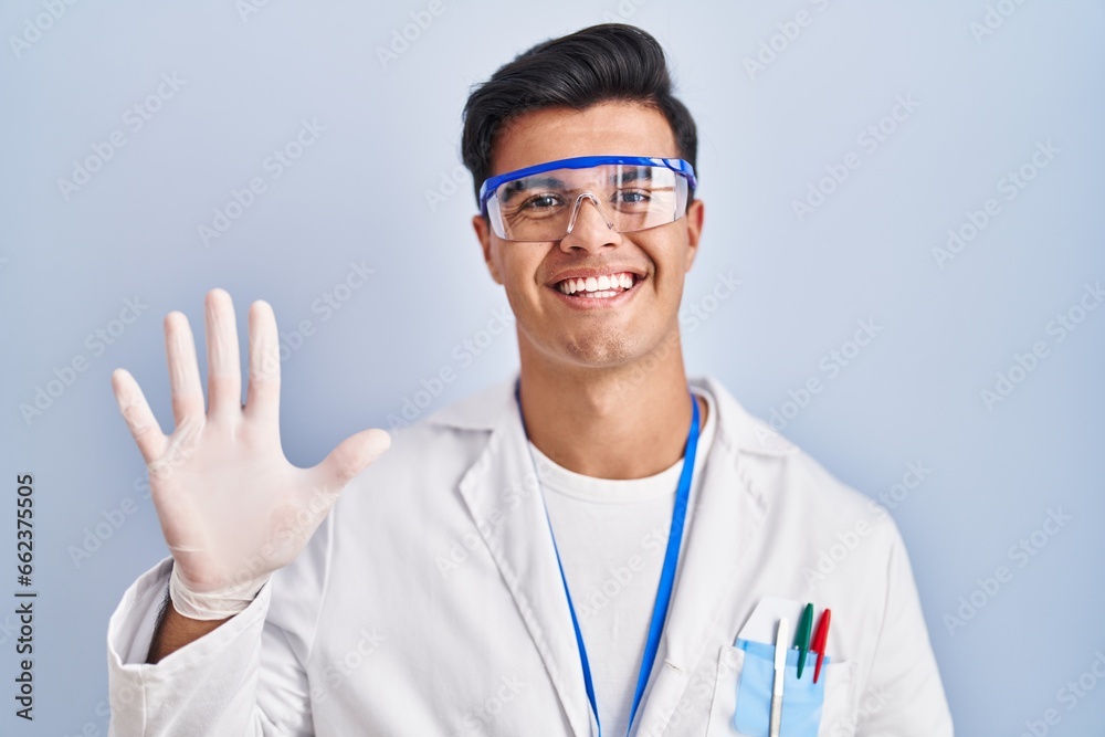 Hispanic man working as scientist showing and pointing up with fingers number five while smiling confident and happy. Hispanic man working as scientist showing and pointing up with fingers number five while smiling confident and happy.