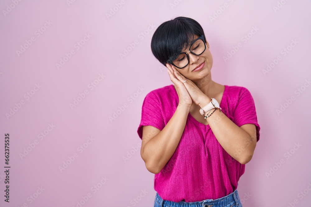 Young asian woman with short hair standing over pink background sleeping tired dreaming and posing with hands together while smiling with closed eyes. Young asian woman with short hair standing over pink background sleeping tired dreaming and posing with hands together while smiling with closed eyes.