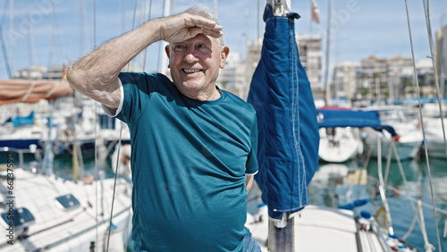 Senior grey-haired man smiling confident doing marine gesture looking around at boat