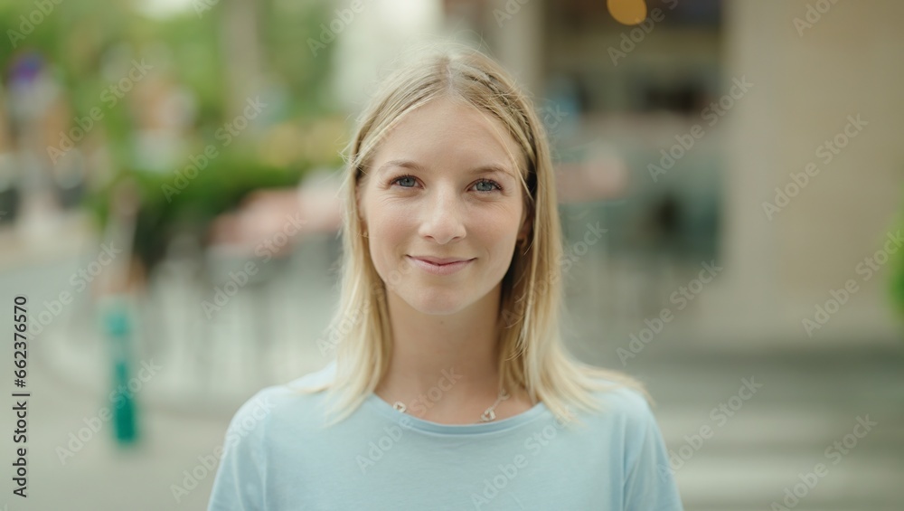 Young blonde woman smiling confident standing at street