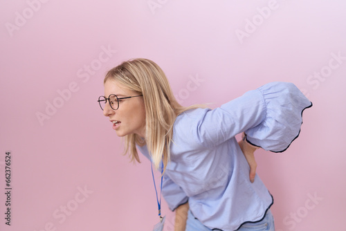 Young caucasian business woman wearing id card suffering of backache  touching back with hand  muscular pain