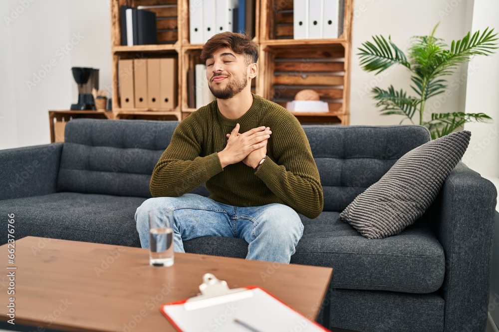 Arab man with beard working on depression at therapy office smiling with hands on chest, eyes closed with grateful gesture on face. health concept. Arab man with beard working on depression at therapy office smiling with hands on chest, eyes closed with grateful gesture on face. health concept.