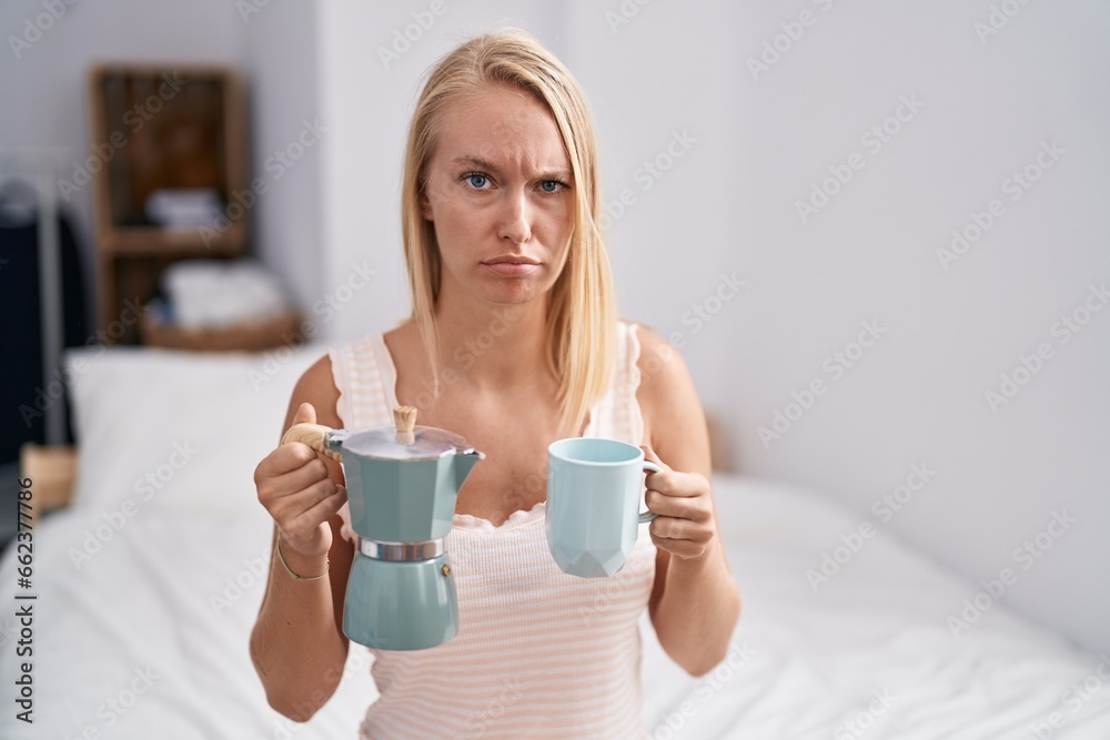 Young caucasian woman drinking coffee on the bed skeptic and nervous, frowning upset because of problem. negative person. Young caucasian woman drinking coffee on the bed skeptic and nervous, frowning upset because of problem. negative person.