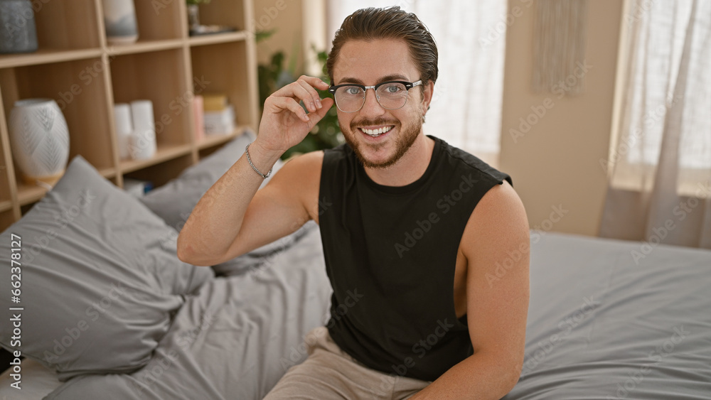 Young hispanic man smiling confident sitting on bed at bedroom