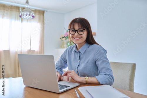 Middle aged business woman working at desk in home office, using laptop