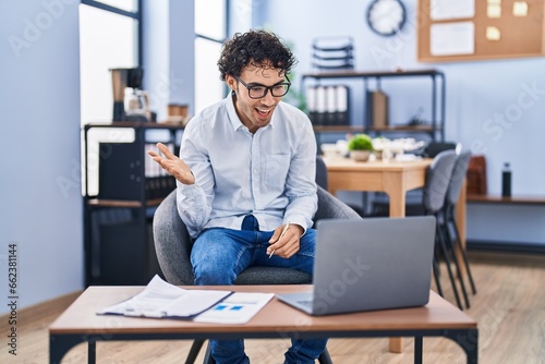 Hispanic man doing video call waving to laptop celebrating achievement with happy smile and winner expression with raised hand