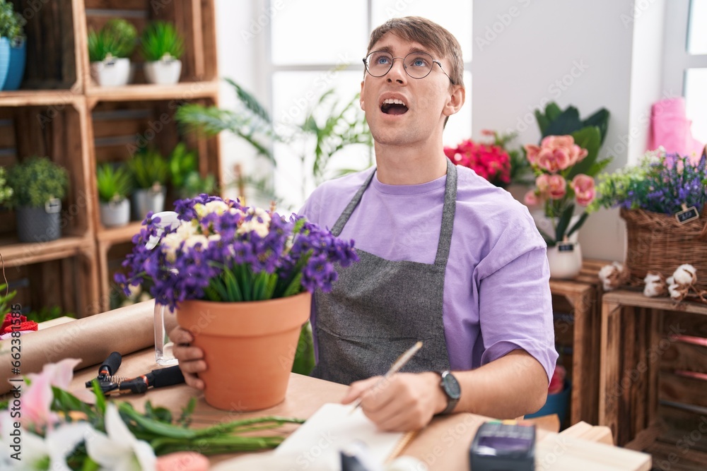 Caucasian blond man working at florist shop angry and mad screaming frustrated and furious, shouting with anger. rage and aggressive concept.