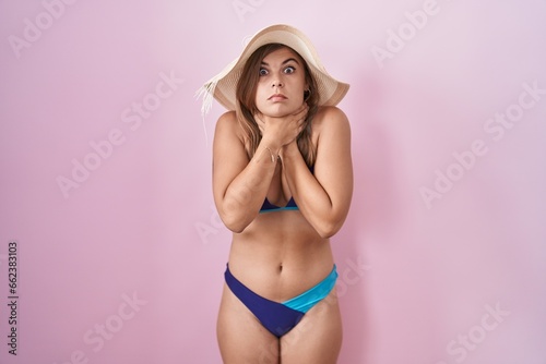 Young hispanic woman wearing bikini over pink background shouting suffocate because painful strangle. health problem. asphyxiate and suicide concept.