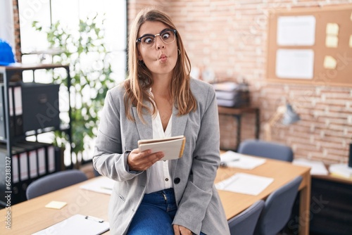 Canvas Print Young hispanic woman working at the office wearing glasses making fish face with lips, crazy and comical gesture