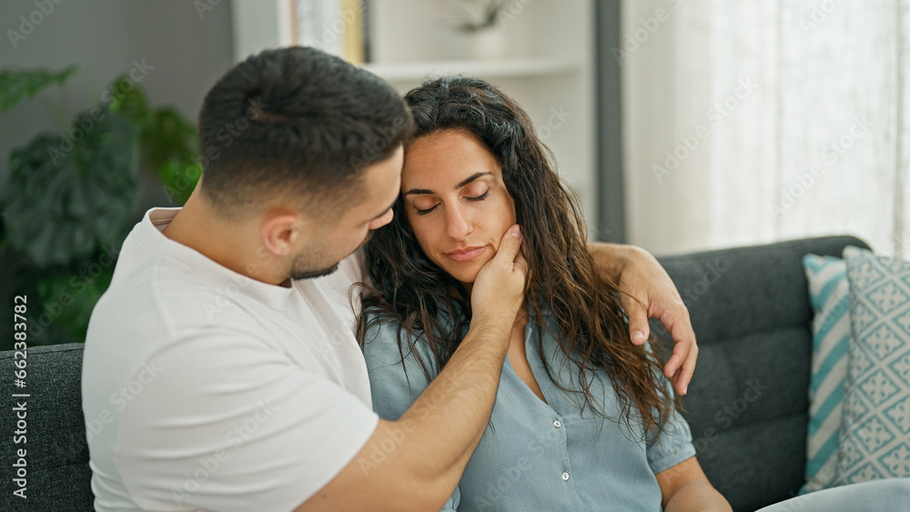 Man and woman couple sitting on sofa consoling girlfriend at home