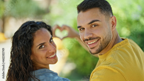 Man and woman couple smiling confident doing heart gesture at park