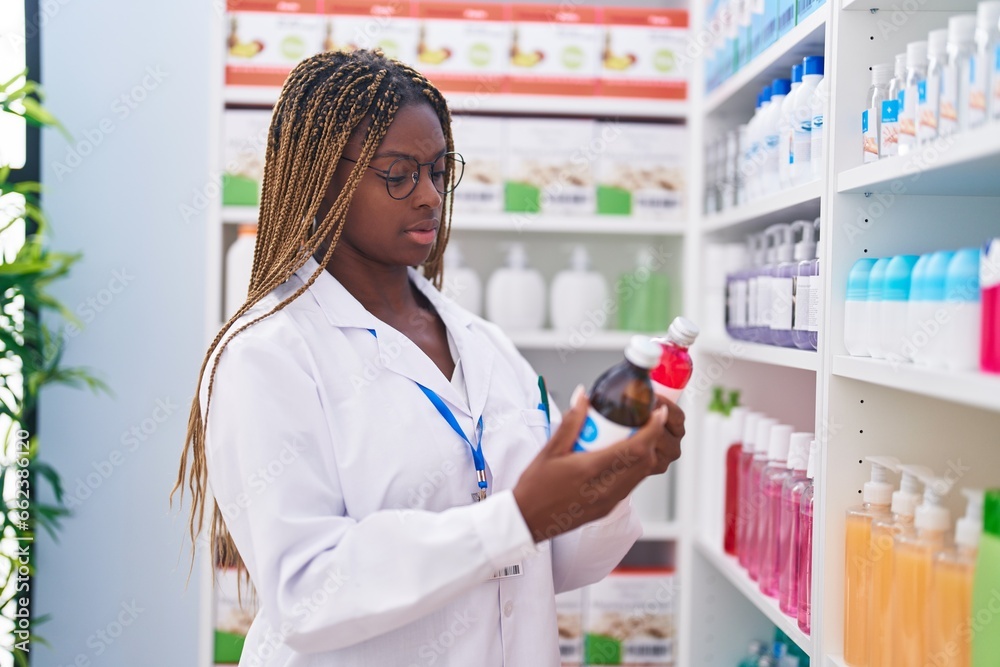 African american woman pharmacist holding medication bottles at pharmacy