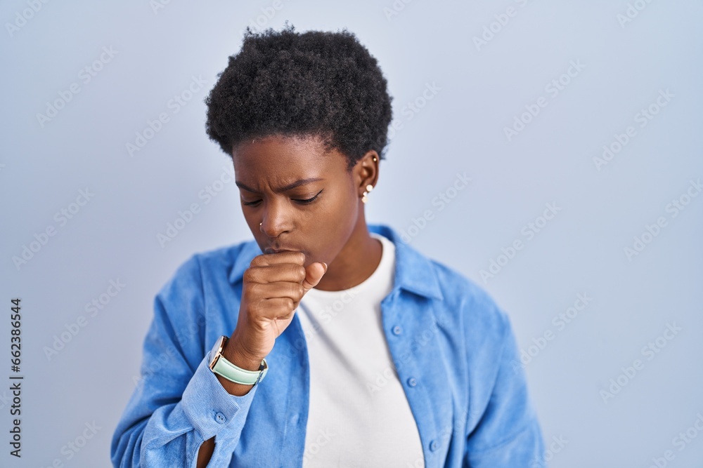 African american woman standing over blue background feeling unwell and coughing as symptom for cold or bronchitis. health care concept.
