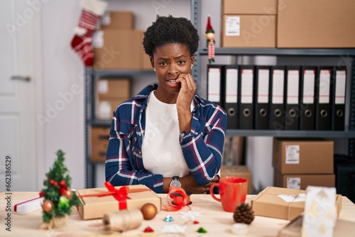 African american woman working at small business doing christmas decoration looking stressed and nervous with hands on mouth biting nails. anxiety problem. photo