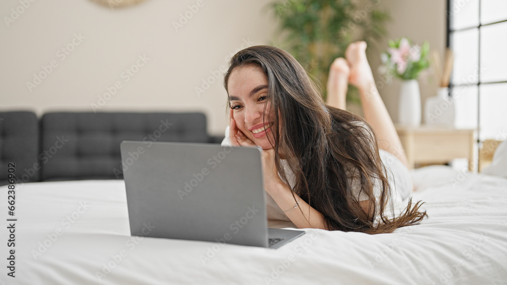 Young beautiful hispanic woman having video call lying on bed at bedroom Young beautiful hispanic woman having video call lying on bed at bedroom