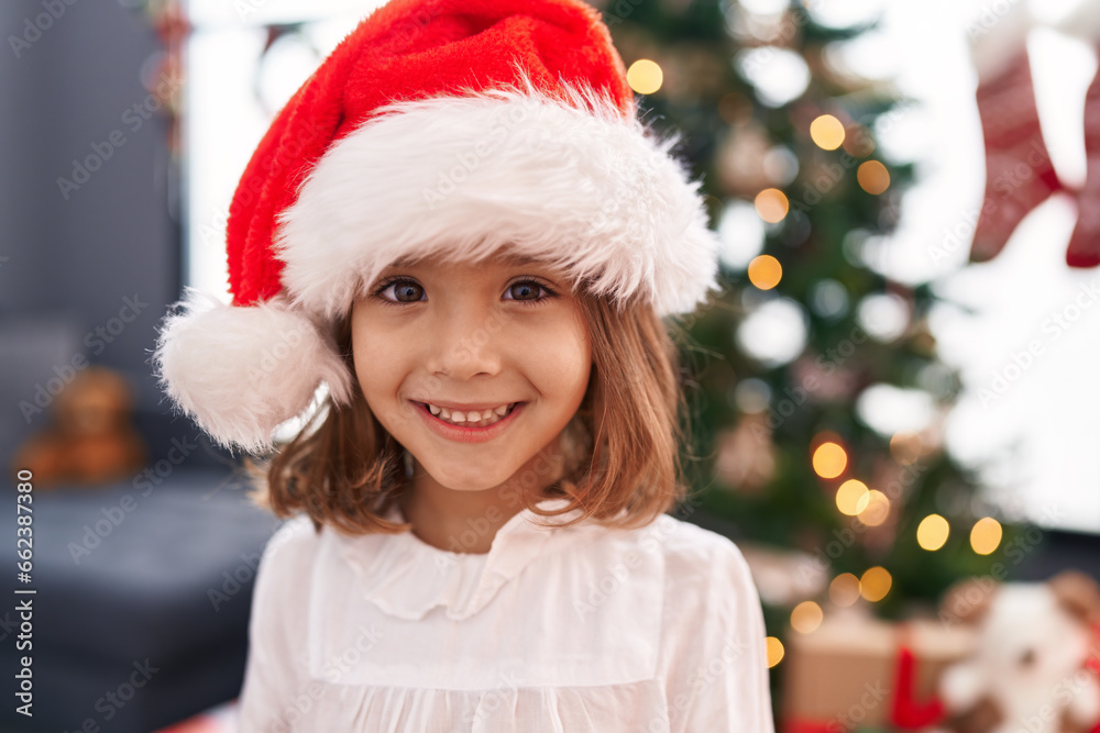 Adorable hispanic girl smiling confident standing by christmas tree at home
