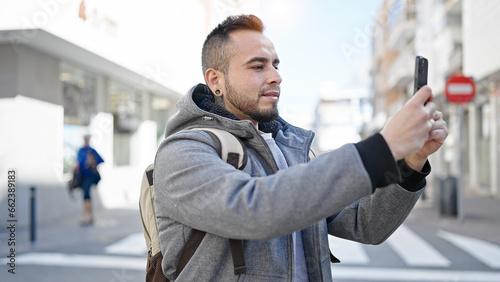 Hispanic man smiling confident taking picture with smartphone at street