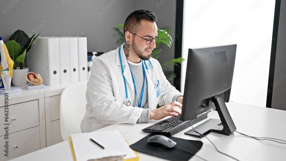 Hispanic man doctor using computer working at the clinic