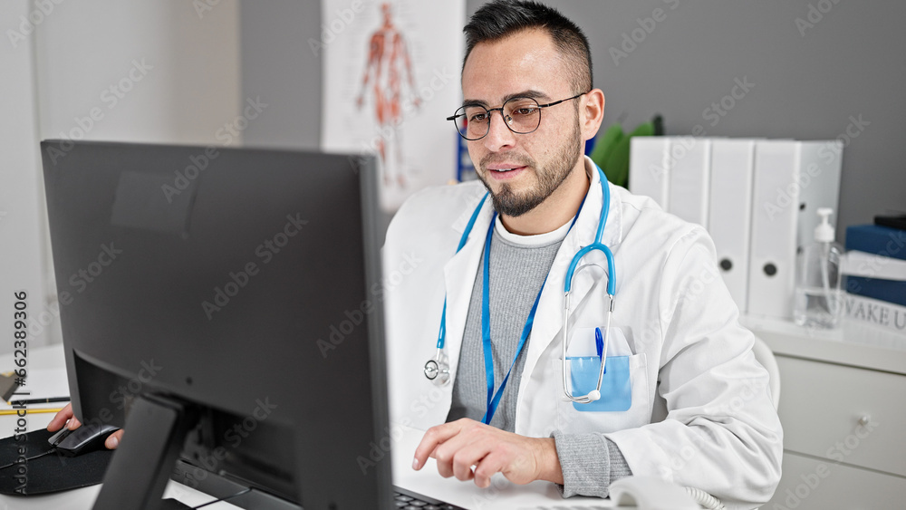 Hispanic man doctor using computer working at the clinic Hispanic man doctor using computer working at the clinic